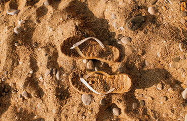 Sand-colored beach slates merge with sand and stones on the seashore. Attributes of rest, summer, relaxation, detachment from problems. Rest at the sea, sandy beach.