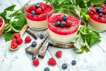 Raspberry Panna cotta with raspberry jelly on a light background. Berry dessert with cream sauce in small jars. place for text