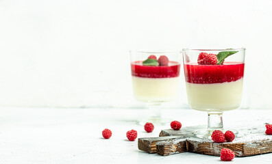 Italian dessert. Raspberry Panna cotta with raspberry jelly on a light background. Berry dessert with cream sauce in small jars. Long banner format. place for text