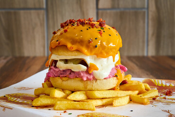 gourmet burger with meat, caramelized onion, tomato, bacon, french fries and dripping cheddar cheese