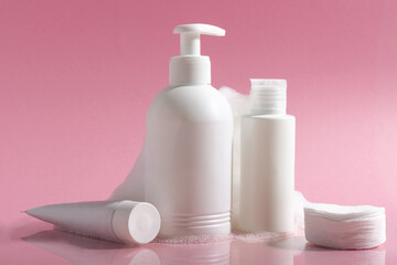 Cosmetics for face, body and hair care. Moisturizer, shampoo or facial cleanser on pink background with foam
