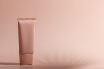 Cosmetic cream or mask in a white tube with hard shadows from the leaves on a white background. Natural organic care for face and body skin. View from above.