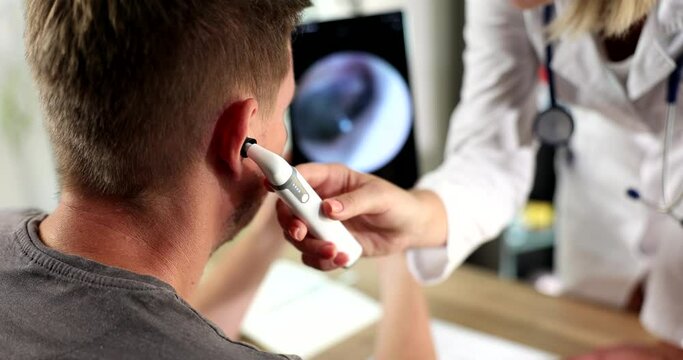 Closeup of male ear being examined with an otoscope doctor