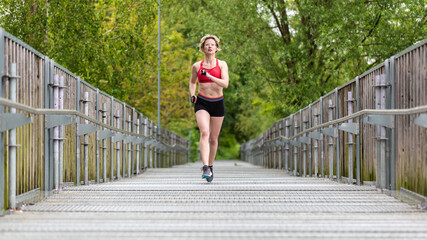 Attractive thirty year old woman in shorts and sports bra running