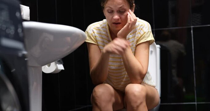Woman nervous sitting on toilet with sick stomach