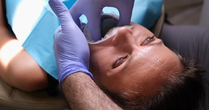 Orthodontist sets dental facial arch on woman face and prostheses