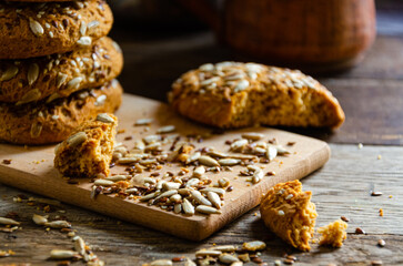 Oatmeal homemade cookies with grains on a wooden board, on the kitchen table and homemade coffee in a clay mug.