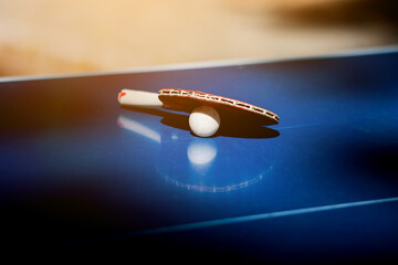 Wooden racket for ping pong and white ball lying on the blue table. table tennis paddles equipment. hobby, activity