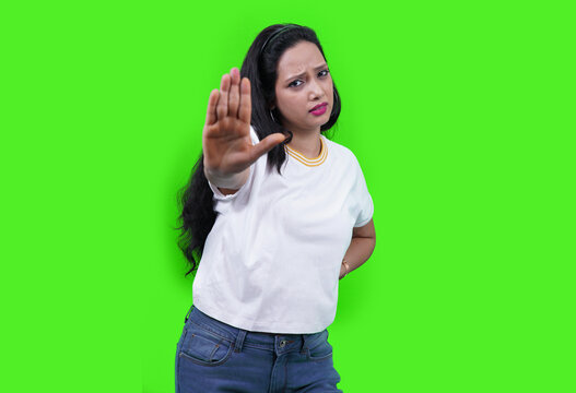 Young Indian Woman Wearing Casual White T-shirt Over Green Studio Isolated Background, Saying No, Doing Stop Sign, Looking Straight In To Camera.