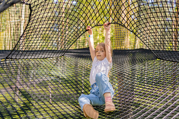 child having fun in net tunnel in playground or amusement park.