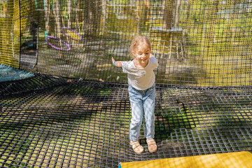 Girl crawls on a net in an obstacle course. Netting amusement park.