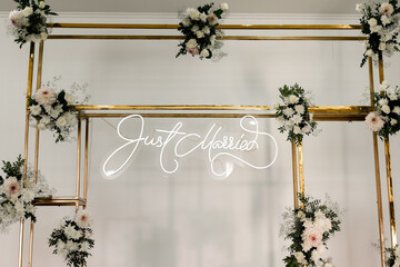 wedding rectangular metal gold arch design with fresh white flowers and greens on a white wall...