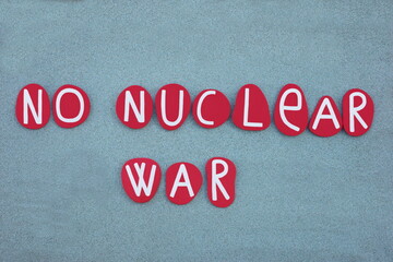 No nuclear war, pacifist slogan composed with red colored stone letters over green sand