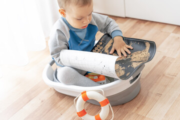 Child play in handmade ship with world map in hands. Summer vacation and travel adventure concept....