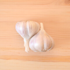Top view of two organic garlic heads on a wooden table.