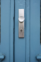 Keyhole with a round handle on a blue wooden door. 