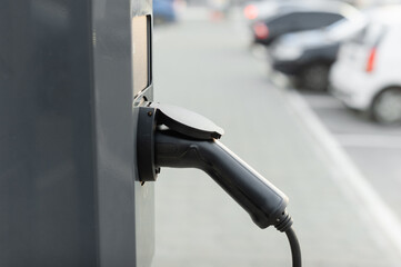 The power cable of the electric vehicle is connected to the high voltage charging station in the equipped parking lot