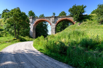 Most kolejowy w Kiepojciach w słońcu z drogą pod mostem