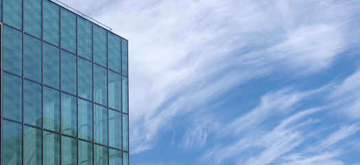 Fototapeta na wymiar Corner of a glass facade building under cloudy blue sky