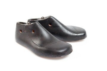 Isolated vintage shoe form child size. Pair of dark wooden cobbler shoe molds for children. Used by shoe makers or cordwainer for manufacturing or repairing shoes. Selective focus. White background.