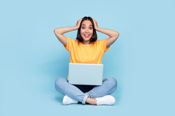 Full body photo of stunning young girl japanese cant believe success netbook dressed stylish yellow look isolated on blue color background