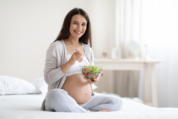 Obraz na płótnie Canvas Attractive pregnant woman eating healthy meal at home