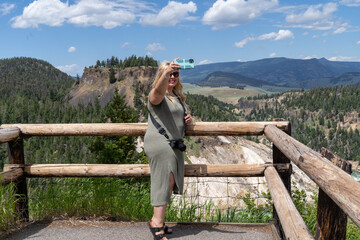 Fototapeta na wymiar Happy woman takes a selfie in Yellowstone National Park