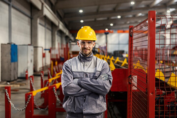 Successful heavy industry worker proudly stands in the facility and looks at the camera.