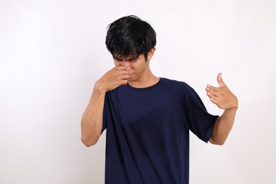 Asian Young Man Standing While Covering His Nose. Bad Smell Concept. Isolated On White Background