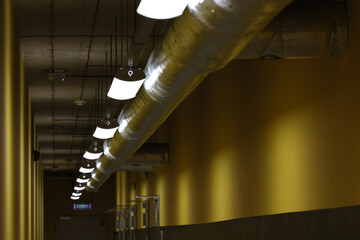 Żółty, długi korytarz z lampami na suficie. Zaplecza.