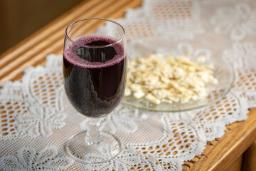 Grape juice in wine glass on table with unleavened matzah bread on lace for Christian church communion 
