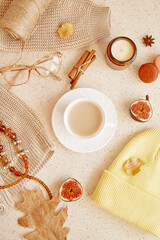 Autumn feminine lifestyle flat lay - casual sweater, woman glasess, hat and accessories. Aesthetic cozy lifestyle among candle, fall leaves, macaroons cinnamon sticks.