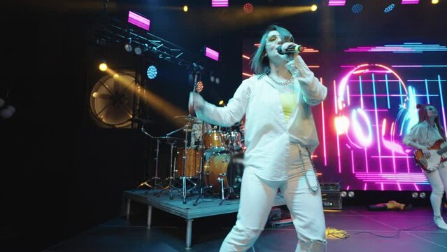young woman is dancing and singing on stage, concert of musical band, hip-hop, rap and rock music