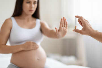 Pregnant woman showing stop gesture to cigarette