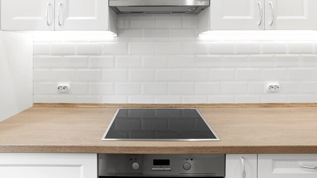 White kitchen with wooden countertop with induction cooktop. Nobody