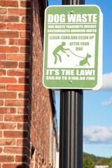 Obraz premium t’s the Law sign posted beside brick mill building reporting dog waste regulation