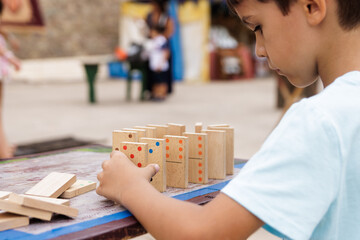 Boy playing with a wooden dominoes outside