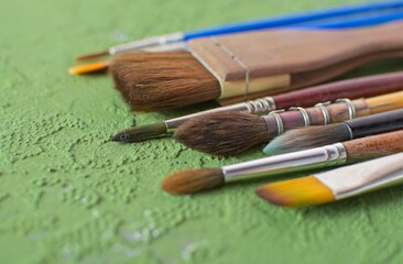 
Close-up of the artist's brush on a green textured background. Selective focus, blur.