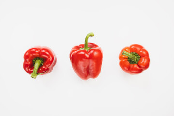 Three sweet red bell peppers on white background. Top view, copy space