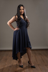 Fototapeta premium wearing a long gala dress and high heels a young woman with long hair posing standing in studio, beauty and elegant fashion, outfit