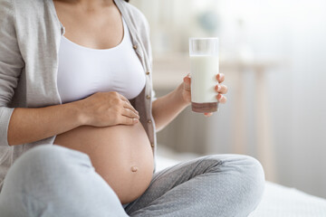 Unrecognizable pregnant woman holding glass of milk