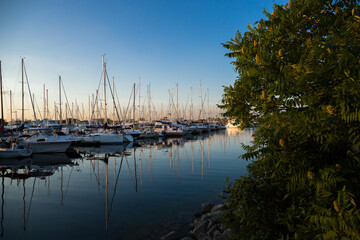 Amazing sunset, boats in the harbor, yachts in a bay of lake at sunset light.
