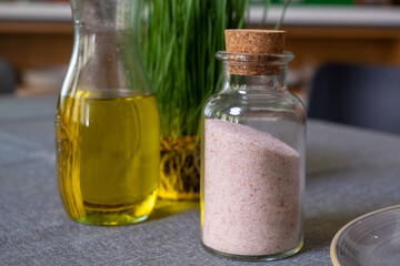 sprouted rye grain with green yolk, olive oil, bottle with salt, on table in kitchen with wooden wall in background, cozy kitchen atmosphere, kitchen advertisement, food poster, space for your text