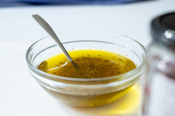 small bowl with olive oil and spices, spoon in bowl on white table, kitchen atmosphere