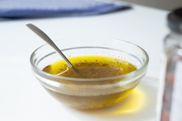 small bowl with olive oil and spices, spoon in bowl on white table, kitchen atmosphere