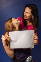 Mãe e filha abraçadas com cartaz em branco para reclame.
