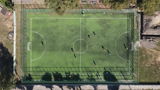 playing football on the football field in sunny weather aerial view, filmed with a drone with a smooth zoom 4K