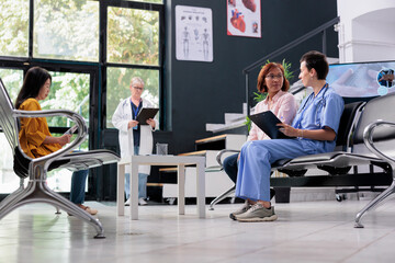 Medical nurse taking notes at examination with senior asian patient, doing checkup consultation in waiting room. Nurse writing report papers at appointment with woman. Medicine concept