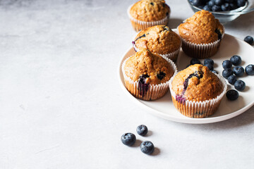 Blueberry muffins served in a plate on a marble background. Copy space. - obrazy, fototapety, plakaty