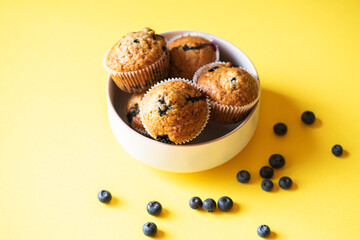 Blueberry muffins served in a bowl on a yellow background. Overhead view. - 535918890